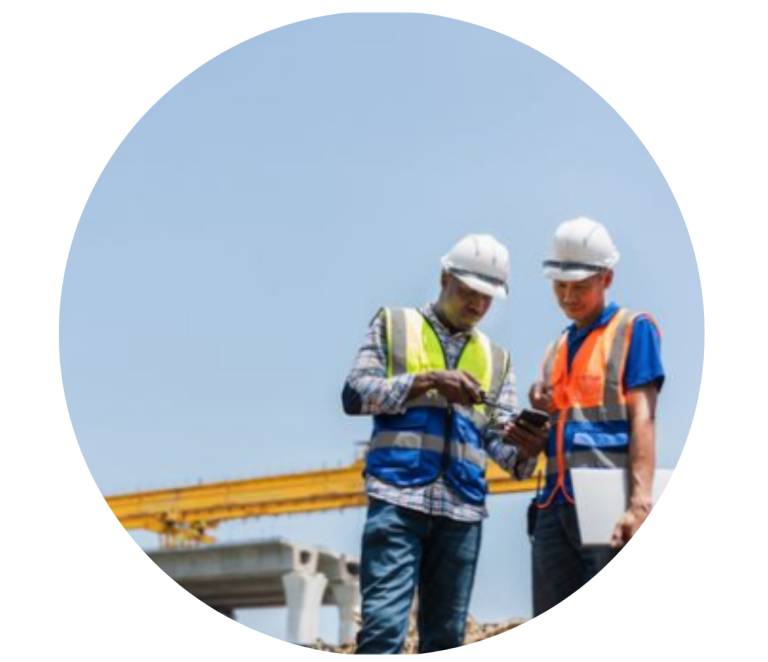 Zwei Bauarbeiter, die auf einer Baustelle zusammen auf ein Handy schauen.